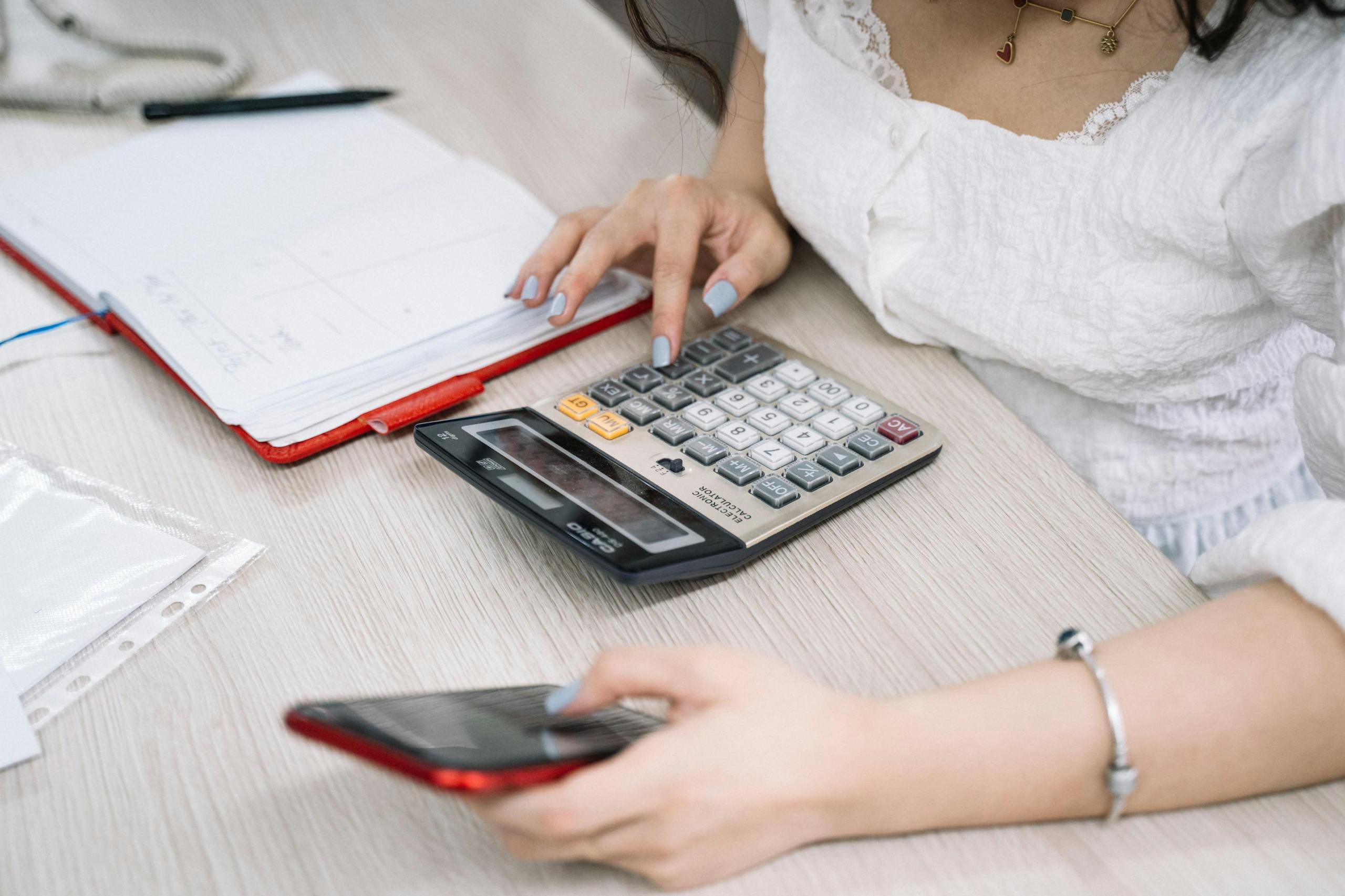 Zesty for Accountants 7 Close-up of a woman using a calculator and phone at her office desk.
