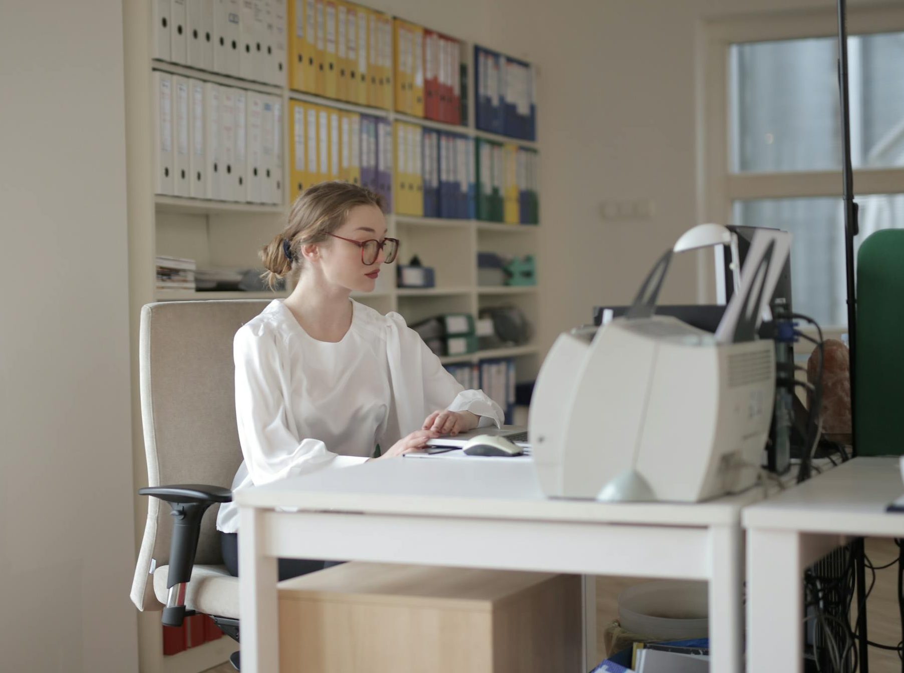 Zesty for Early Childhood Education | ECE Admin 2 Focused woman working in a modern office filled with files and equipment.