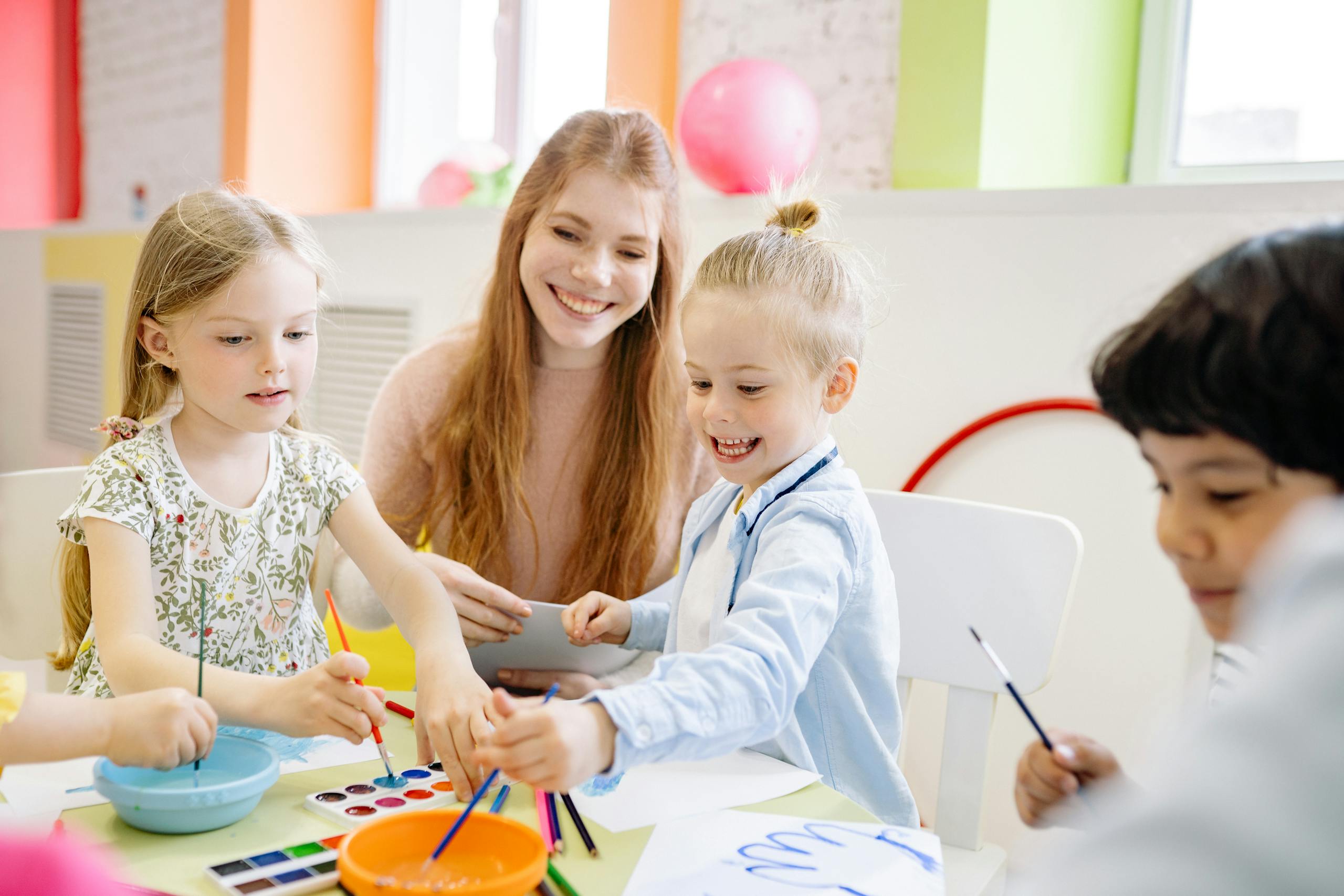 Zesty for Early Childhood Education | ECE Admin 1 Zesty Virtual Assistants: Early Childhood Education Services | Young children enjoy painting with a teacher in a vibrant classroom setting.